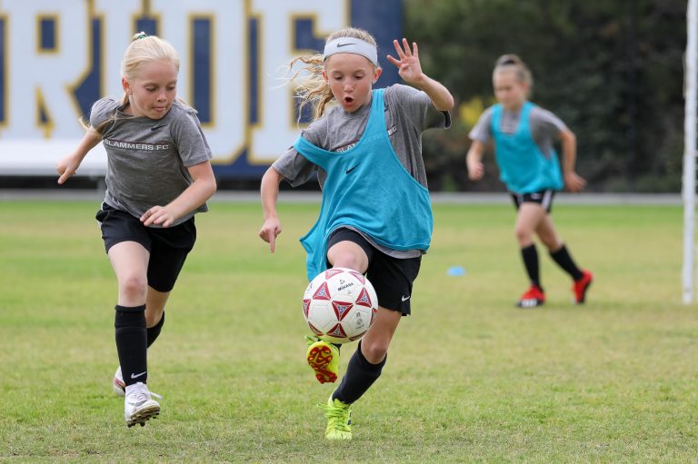 two girls running after a soccer ball