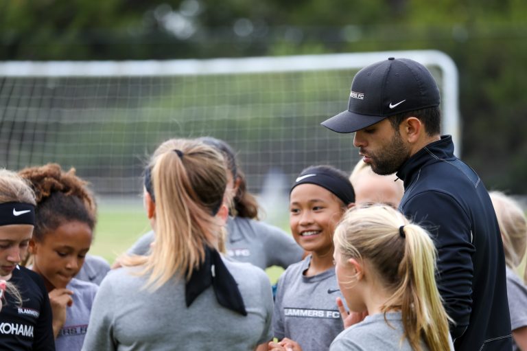 huddle of girls soccer players with Coach Pete Aguirre